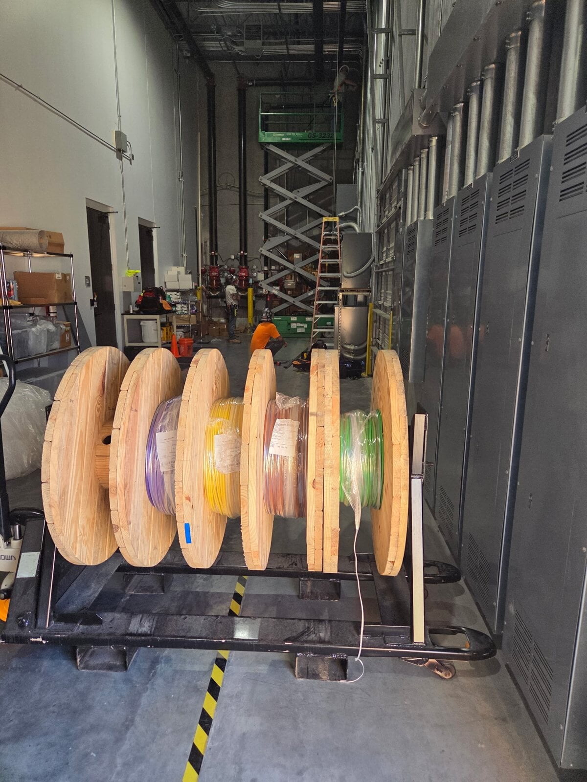 Reels of color-coded wire staged beside a lineup of electrical switchgear for an industrial wire pull in La Porte, TX